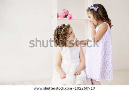 Cute little girls in white dresses talking. Little princess, white studio, joy, laughter and happiness.