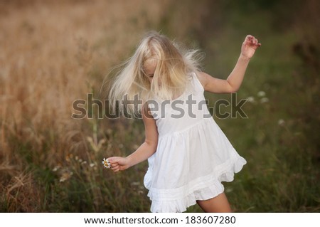 Little cute girl walks in the summer field. Happiness, joy, dance and smile.