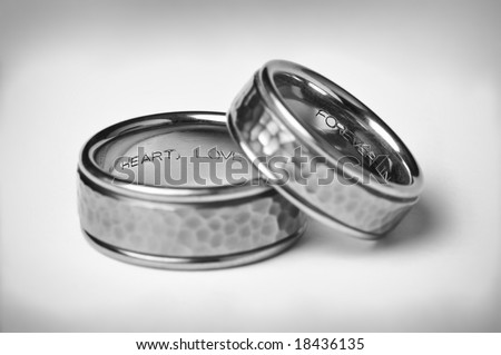 Two Titanium Silver Wedding Bands with heart, love, and forever inscriptions on a white gradient background symbolizing marriage.