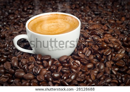 Cup of Morning Espresso in Dark Roasted Coffee Beans background steaming with frothy cream on top