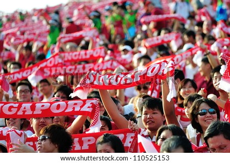SINGAPORE - AUGUST 09: Enthusiastic audience waving the red Singapore scarves during National Day Parade 2012 on August 09, 2012 in Singapore