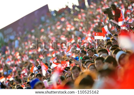 SINGAPORE - AUGUST 09: Audience waving Singapore flags during National Day Parade 2012 on August 09, 2012 in Singapore