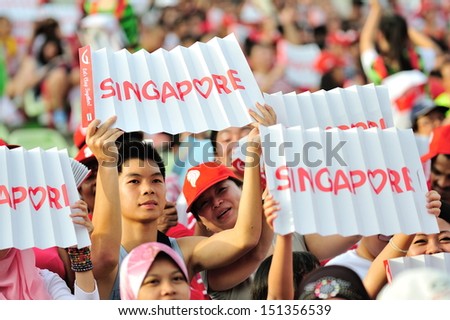 SINGAPORE - JULY 20: Spectators waving Singapore banners during National Day Parade (NDP) Rehearsal 2013 on July 20, 2013 in Singapore