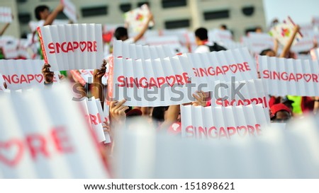 SINGAPORE - JULY 20: Spectators waving Singapore banners during National Day Parade (NDP) Rehearsal 2013 on July 20, 2013 in Singapore