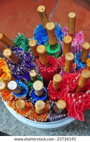 Colorful traditional umbrellas placed in a bucket for sale