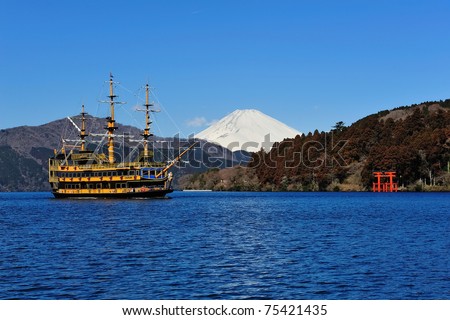 Hakone Lake, Mount Fuji and the famous pirate sight seeing ship in Japan, with a torii gate from Hakone\'s shrine at the far end shore of the lake