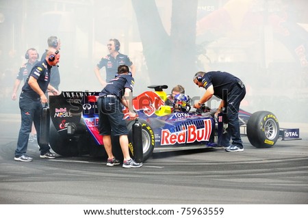 SINGAPORE - APRIL 24: Red Bull Racing pit crews cool the F1 RB6 car after David Coulthard performed donuts during Red Bull Speed Street Singapore on April 24, 2011 in Singapore.