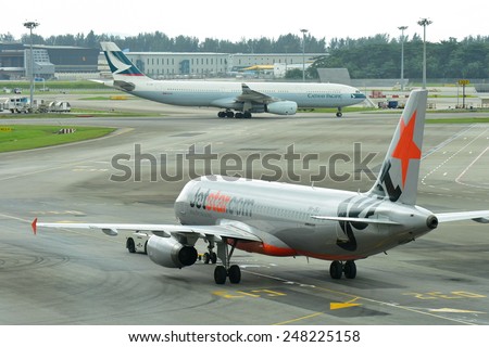 SINGAPORE - JANUARY 10:  Jetstar Asia Airbus 320 preparing for departure as Cathay Pacific Airbus 330 taxi past at Changi Airport on January 10, 2015 in Singapore