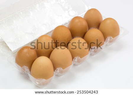 Natural flesh brown colored chicken eggs in translucent plastic tray on white background