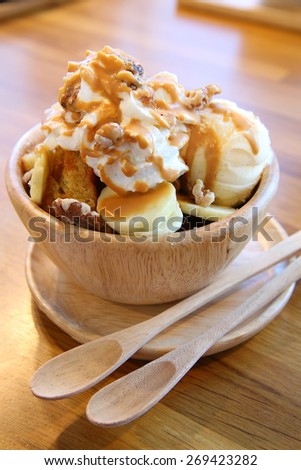 Homemade Toasted Bread with Vanilla Ice Cream, Bananas Topping with Whip-Cream, Pecans and Caramel Syrup in Wooden Bowl