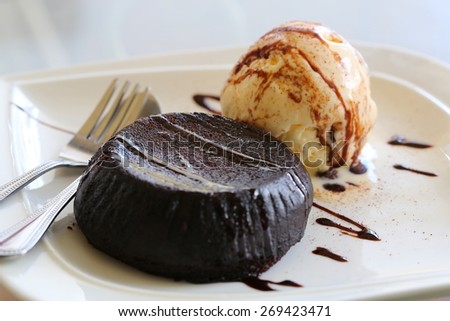 Homemade Chocolate Lava Cake with a Scoop of Vanilla Ice Cream Topping with Chocolate-Caramel Syrup on White Ceramic Plate
