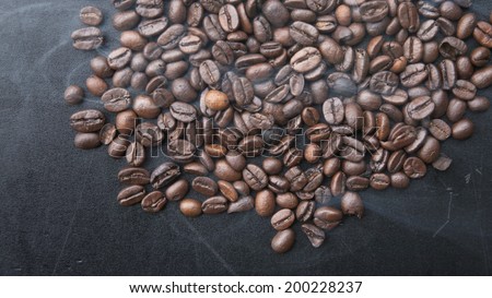 Roasting coffee beans with smoke on black background.