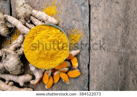 Turmeric powder and turmeric on wooden background .- Vintage Filter Processing.