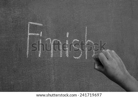 Hand pointing at finish word of success concept on chalkboard