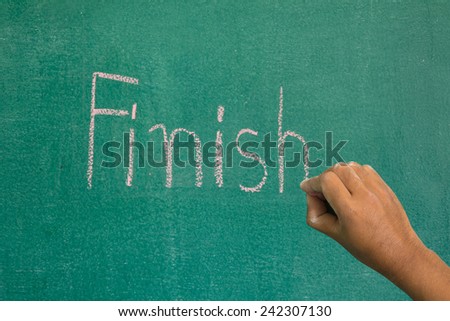 Hand pointing at finish word of success concept on chalkboard