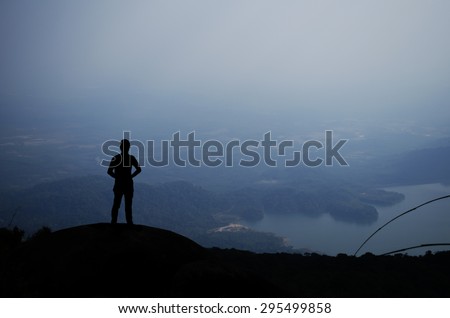 Man silhouette on top of a high mountain to see the scenery, background Hem chest and white light from the sun.