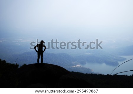 Man silhouette on top of a high mountain to see the scenery, background Hem chest and white light from the sun.