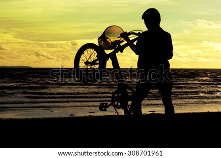 Children and bike silhouette on the sand beach.