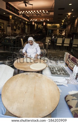 ISTANBUL, TURKEY - MAY 19, 2011: A woman, dressed  traditionally, in Istanbul, Turkey, on May 19, 2011, molds dough, in order to make some traditional turkish food, as part of her job in a restaurant.