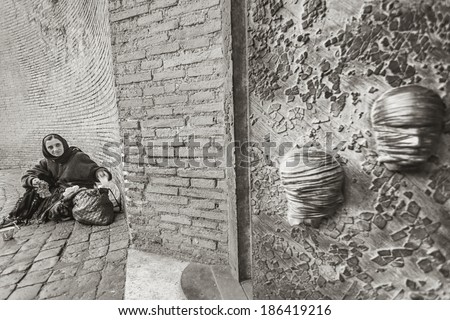 ROME, ITALY - APRIL 11, 2010: An old, poor woman, outside a church in Rome, Italy, on April 11, 2010, seats on the ground, outside, with a bag of stuff next to her, while she begs due to her poverty.