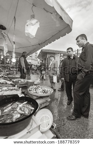 ISTANBUL, TURKEY - MAY 20, 2011: People in the fish market, decide what to buy, while the fisherman watches people passing by, and tries to sell his catch in order to make a living.