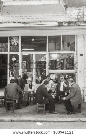 ISTANBUL, TURKEY - MAY 22, 2011: A group of men seat outside a coffee shop, having a discussion and socializing. A popular way for men in Turkey to gather and communicate each other, are coffee shops.