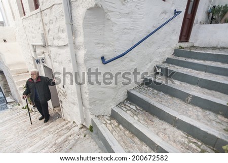 SYROS ISLAND, GREECE - MARCH 4, 2012:  An old man stands, taking a rest, after ascending the stairs of the settlement he lives. He is used to move around the town on foot, as there is no other way.
