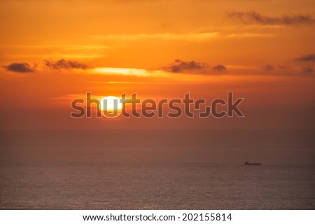The sun sets at the Aegean sea between some clouds, during summer, as viewed from the island of Karpathos, Greece.