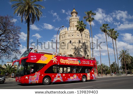 SEVILLE, SPAIN - MAY 16: A City Sightseeing tour bus at the Torre de Oro on May 16, 2013 in Seville, Spain. City Sightseeing operates in 100 cities worldwide and carries 8 million passengers per year.