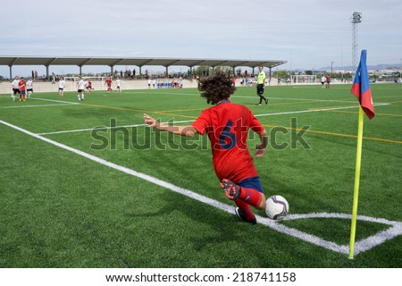 VALENCIA, SPAIN - SEPTEMBER 20, 2014: An unknown youth player taking a corner kick during a youth soccer match. Soccer is the most popular sport in Spain.