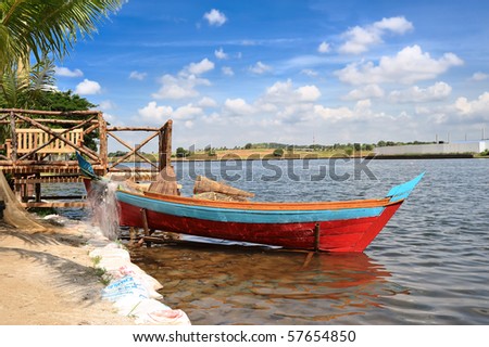 Malay fishing boat (sampan) at the pier with fishing nets and bamboo fish traps.