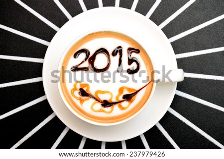 A cup of coffee with foam milk art 2015 pattern in a white cup on white line and black background