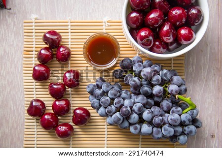 Cherry and grape fruits and juice grass on wooden table