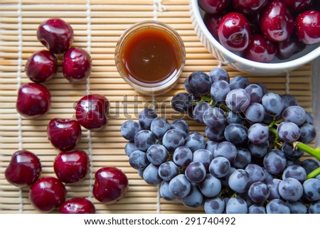 Cherry and grape fruits and juice grass on wooden table