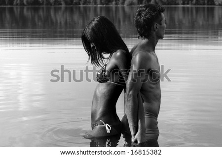 Man and woman are standing back to back in water / black and white photo
