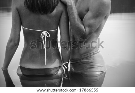 A man embraces a woman standing in the water / black and white photo