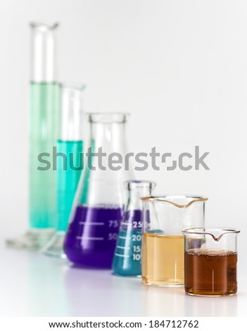 Various lab equipment, glass beakers, Erlenmeyer flasks filled with colored liquids