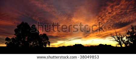Red, yellow and gold clouds at sunset over desert landscape at Arches National Park, Utah, USA.
