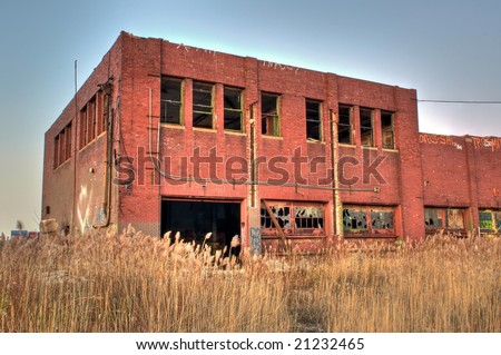 stock-photo-abandoned-brick-warehouse-surrounded-by-overgrown-grass-21232465.jpg