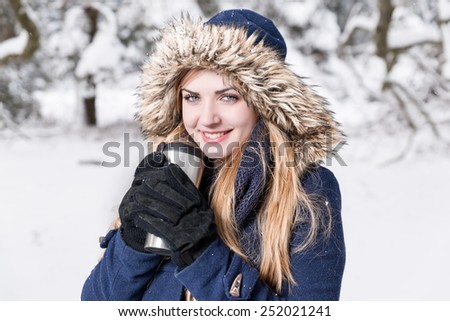 Young women with a jug full of coffee is smileing in a snow world