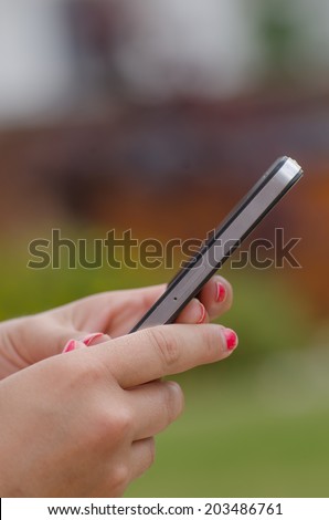 Woman with phone outside, green grass, sunny day
