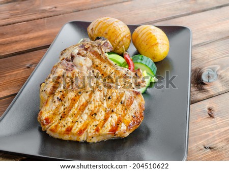 Grilled cutlet with vegetables and roasted potatoes on dark plane