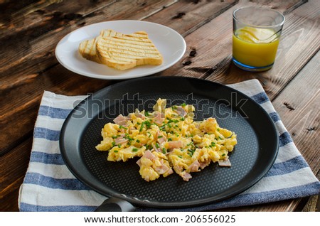 Scrambled eggs on frying pan on wood
