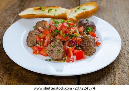 Meatballs with spicy tomato salsa, baked baguette and basil on top