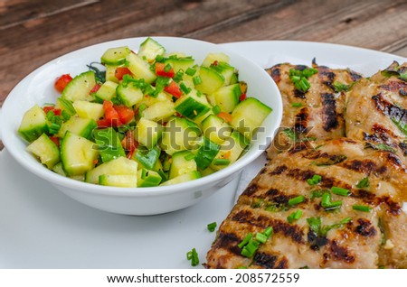 Ground turkey fillet with spring onion, garlic on grill and spicy cucumber salad