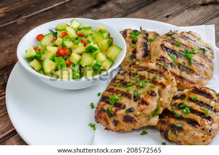 Ground turkey fillet with spring onion, garlic on grill and spicy cucumber salad