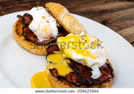 Benedict eggs with crispy bacon and hollandaise sauce on toasted Maffin on clean plate