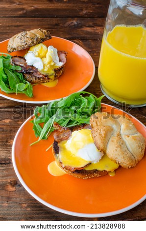 English muffin with bacon, egg benedict with hollandaise sauce and arugula salad, fresh orange juice