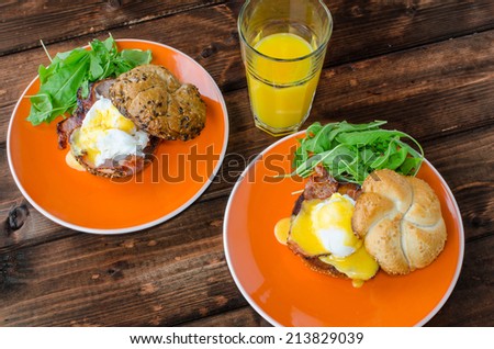 English muffin with bacon, egg benedict with hollandaise sauce and arugula salad, fresh orange juice
