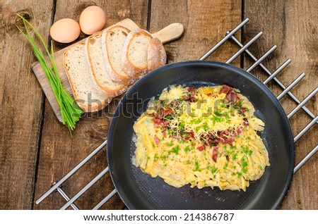 Omelet with bacon and cheese, home bread and chive on top, on frying pan